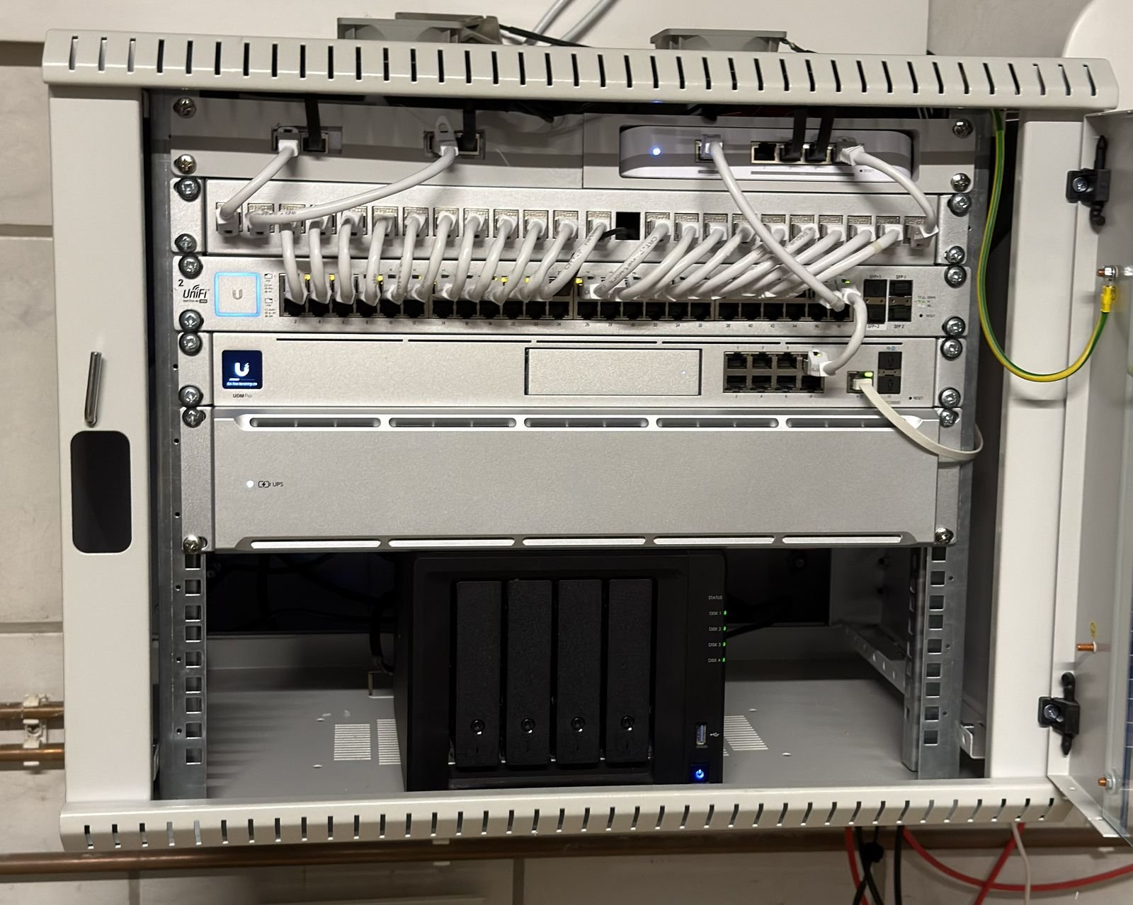 Wandschrank mit Router, Netzwerk-Switch, Patchfeld und einem NAS-Speicher, ordentlich verkabelt